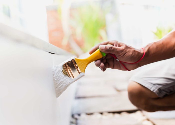 Hand painting outside wall with white color.